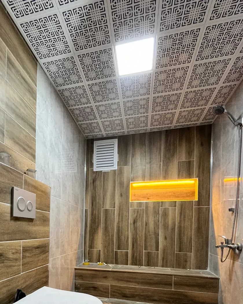 Ahşap görünümlü seramik kaplı duşta LED aydınlatmalı niş, desenli tavan paneli ve kare LED armatür
